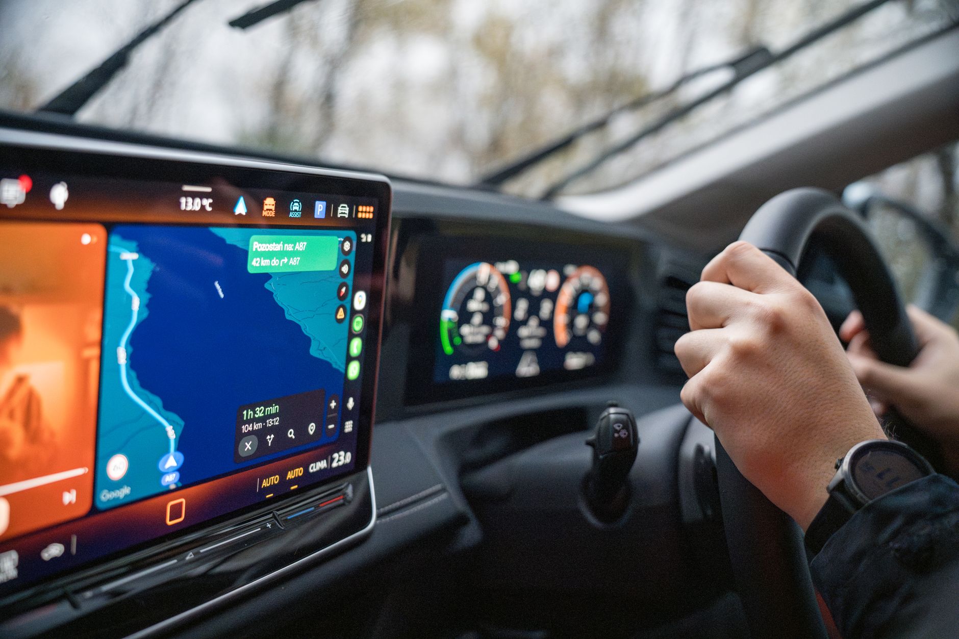 Kierowca trzyma kierownicę, na ekranie systemu infotainment widoczna nawigacja